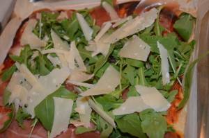 Pizza con crudo, rucola e scaglie di parmigiano